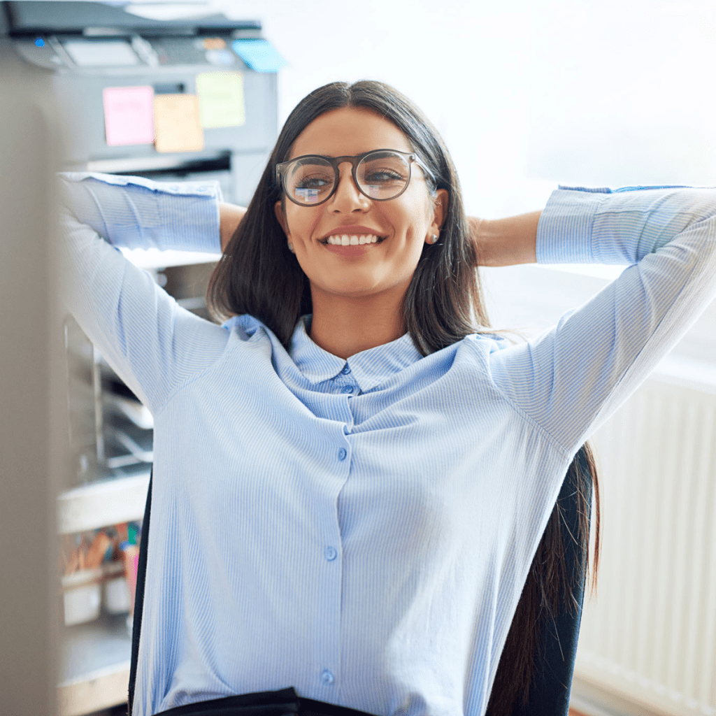 Humanitru Smart Automation woman relaxes at a desk with her hands behind her head